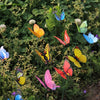 A collection of colorful butterfly garden stakes with various butterfly shapes and colors growing in green foliage.