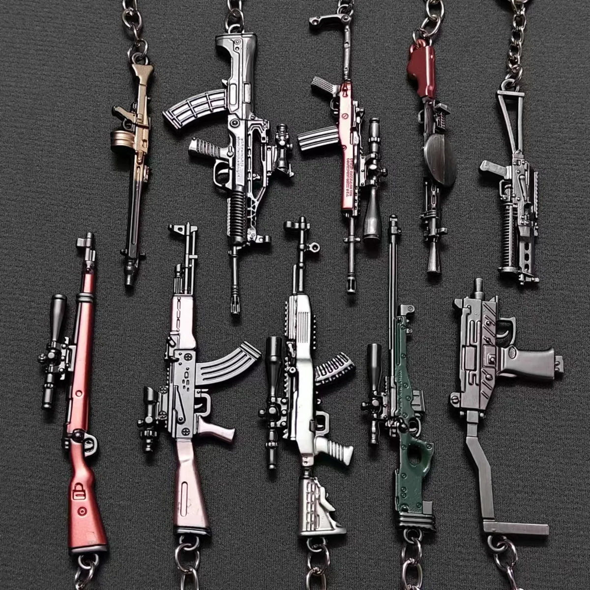 A collection of realistic miniature gun models on metal keychains.