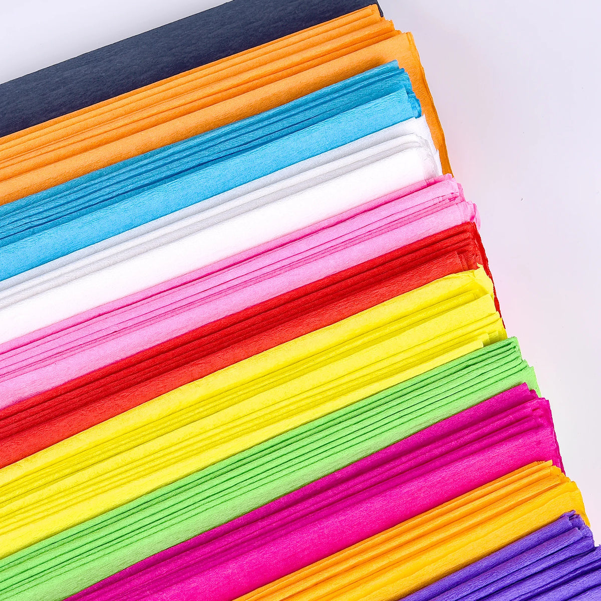 A stack of ten packs of colored crepe paper in various shades including orange, blue, pink, yellow, green, and purple.