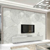 A modern interior featuring a large wall panel with a leaf pattern and a mounted television above a white console.