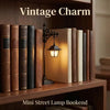 A wooden bookshelf displaying vintage-style books and a small black street lamp bookend with a warm glow.