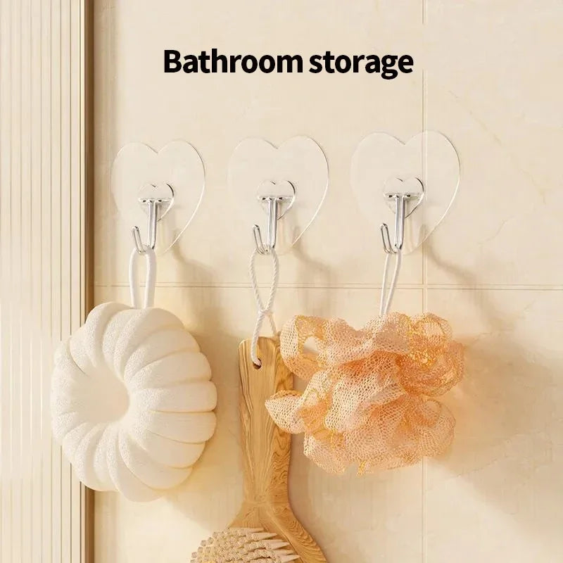 A set of transparent self-adhesive hooks is displayed on a wall, holding white and orange textured items.