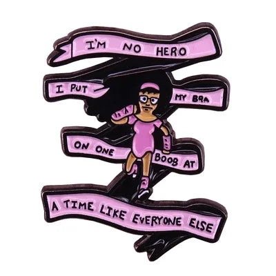 A black enamel pin badge featuring text on a banner with a depiction of a woman.