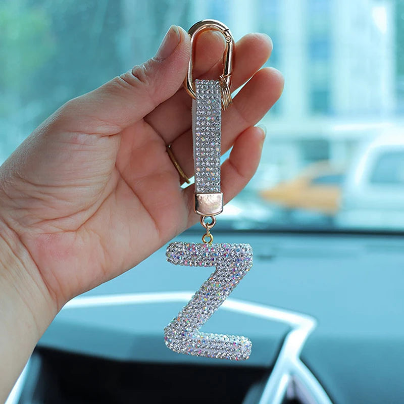 A hand holds a crystal letter keychain charm shaped like the letter Z.