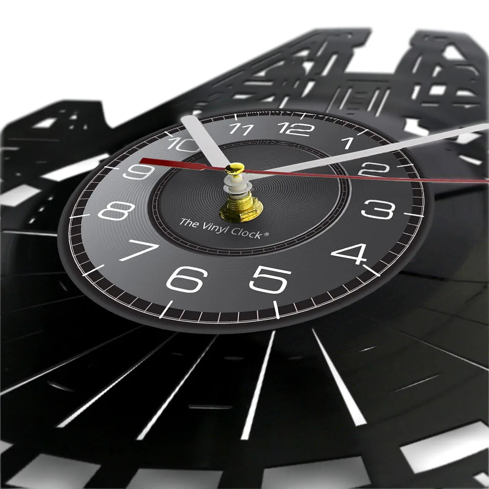 A close-up of a black vinyl record wall clock with a gold-colored pendulum and white markings.