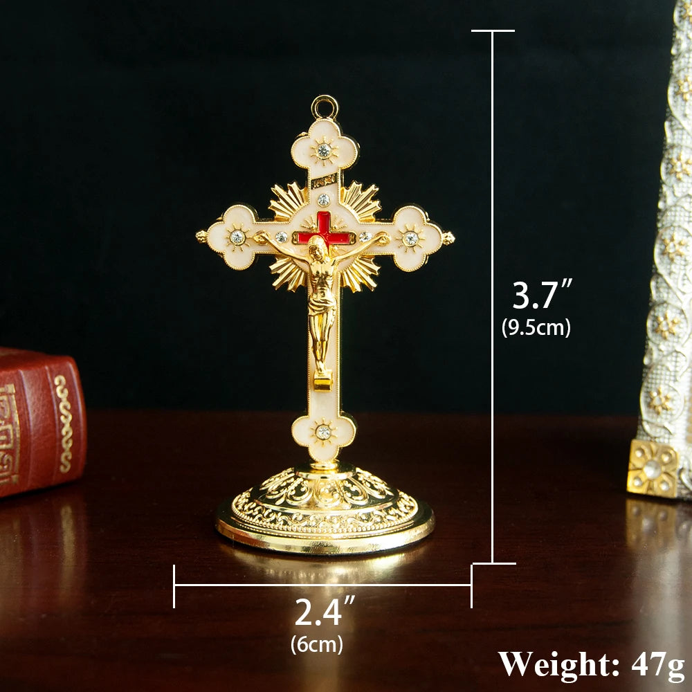 A gold-colored metal Jesus cross ornament with a decorative base, shown against a dark background.