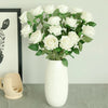 A white artificial silk rose bouquet in a ceramic vase displayed on a gray surface.
