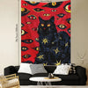 A vibrant red tapestry featuring multiple stylized eyes and a large black cat with yellow star accents.