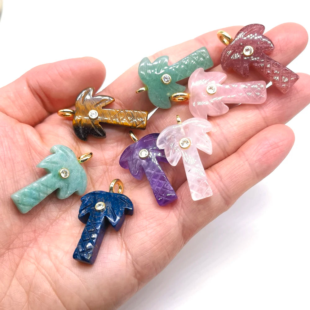 A hand holds several natural crystal pendants featuring various colors including green, pink, purple, and amber.