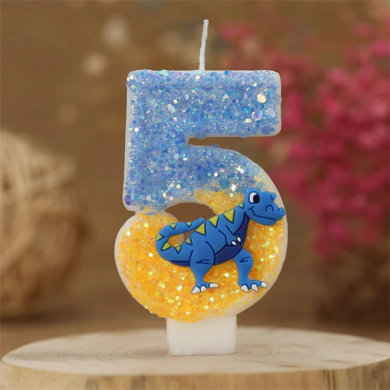 A birthday candle shaped like the number 5 made of blue and yellow glitter, featuring a dinosaur design.