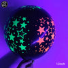 A dark latex balloon filled with neon glow-in-the-dark stars, held by a hand.