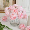 A bouquet of pink silk peony artificial flowers in a glass vase on a white surface.