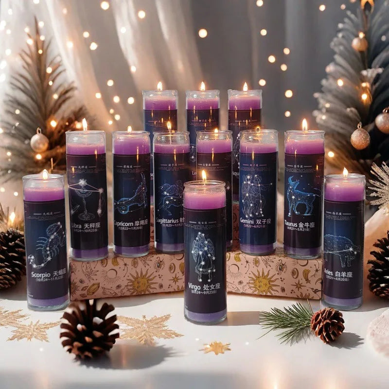 A collection of dark purple glass candles featuring zodiac signs set against a soft, festive background with pine branches.