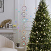 A decorated Christmas tree with sparkling lights and hanging crystal ornaments in a bright room.