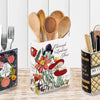 A ceramic book-shaped vase with a vintage finish displayed alongside various kitchen utensils and floral arrangements.
