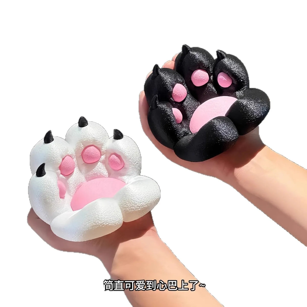 A hand is holding a black silicone cat paw phone stand with pink accents.