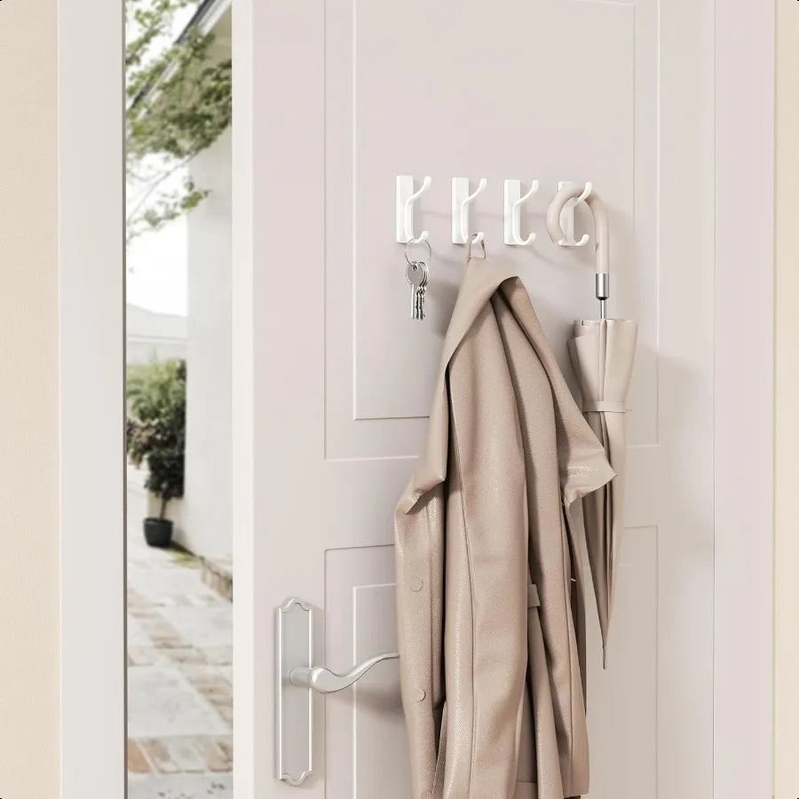 A beige leather jacket is hanging on a white door with four silver self-adhesive wall hooks visible.
