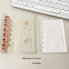 A clear plastic binder cover with a rose gold spiral and a white sheet protector is shown next to a white keyboard.