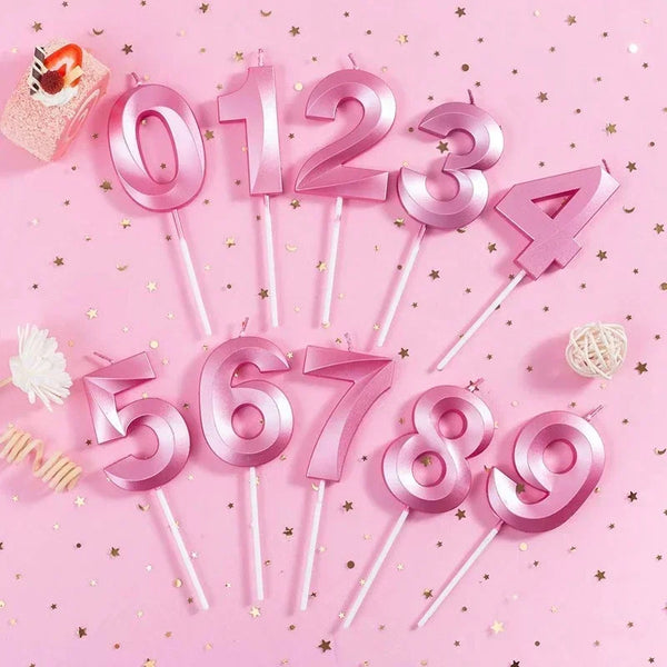 Pink birthday candles shaped like numbers 0 through 9 arranged on a pink background.