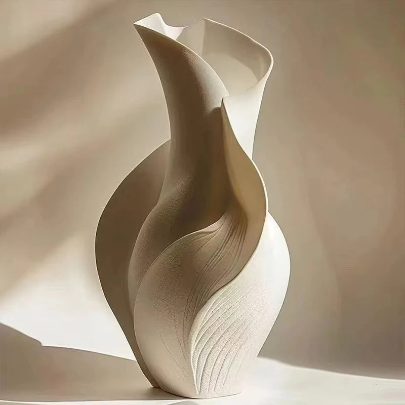 A beige ceramic vase with an abstract, flowing grass motif, photographed in soft natural light.