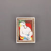 A framed painting featuring a serene figure in yellow and white against a red background, used as a fridge magnet.