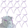 A white cake decorated with silver and lavender ribbon bow toppers in a coquette style