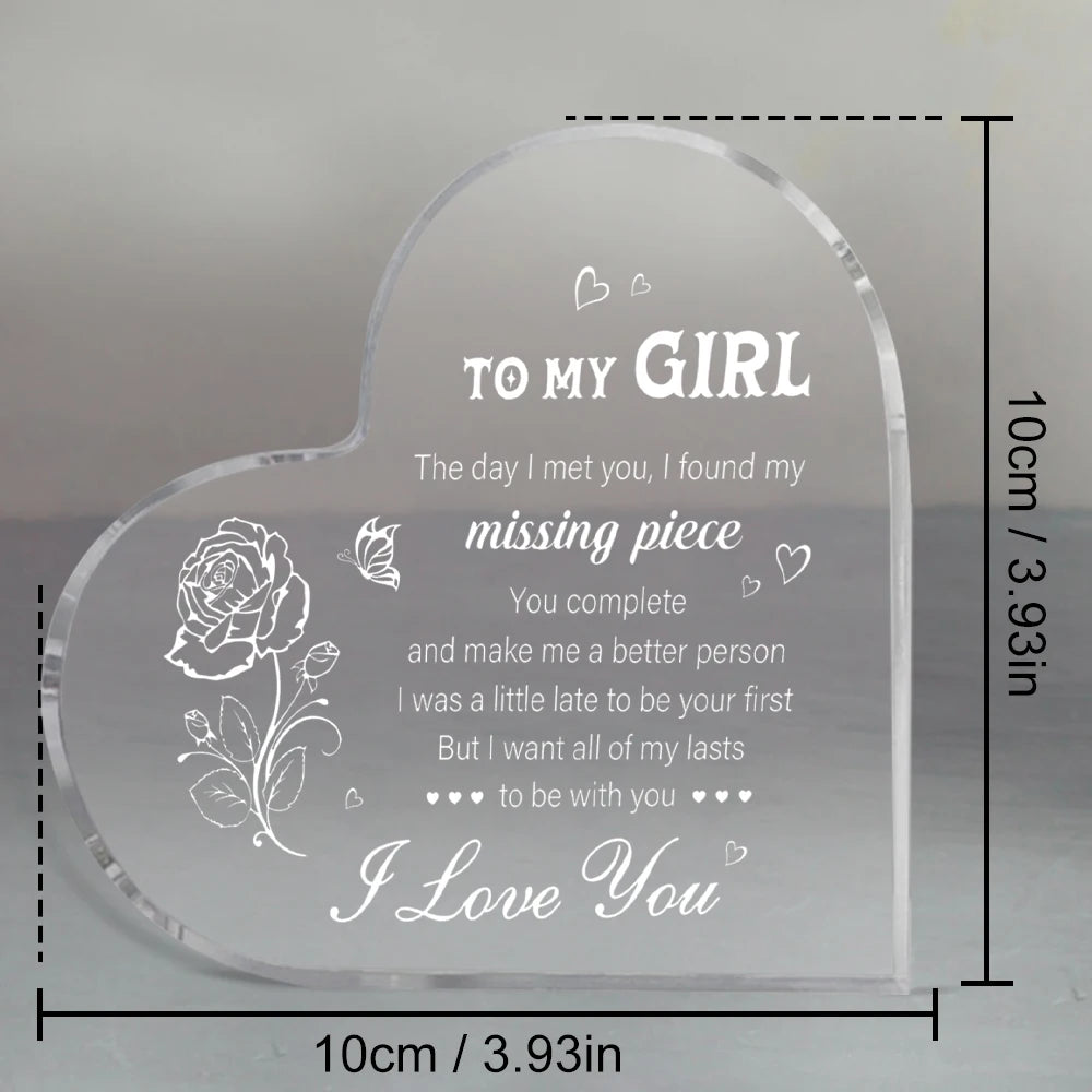 A clear heart-shaped acrylic keepsake engraved with a message to a girl and a rose design.
