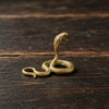 A golden brass snake sculpture coiled on a dark wooden surface.