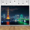 A photograph of the Tokyo skyline at night featuring the Tokyo Tower and a large suspension bridge reflecting on the water.