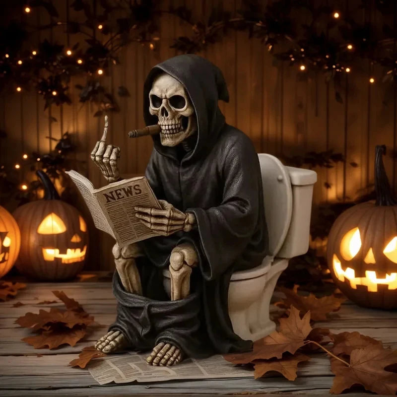 A dark resin statue of a skull wearing a hood and holding a newspaper sits on a toilet, decorated for Halloween.