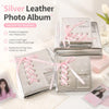 Silver leather photo album with pink ribbon ties displayed on a white surface.