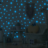 A gray wall decorated with blue glow-in-the-dark star decals and a giraffe stuffed animal