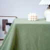 A light green cotton rectangle tablecloth is draped on a table, featuring a cluster of white decorative balls.