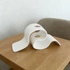 Jarrón decorativo moderno curvo impreso en 3D de color blanco sobre una mesa de madera.