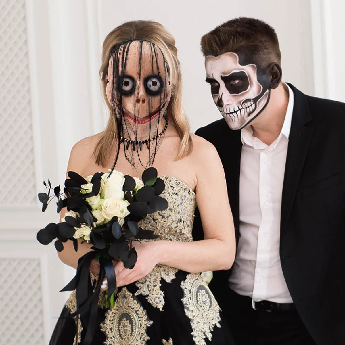 A woman wearing a full face horror costume mask and holding a bouquet of white and black flowers next to a man with a skull m