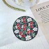 A circular silver ornament featuring red and white floral crystal designs on a dark background.
