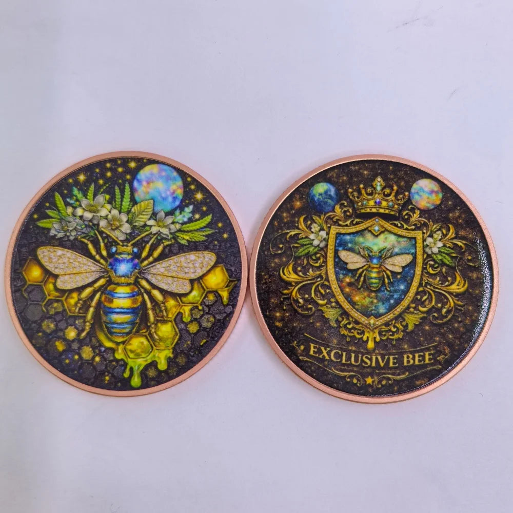 A pair of gothic copper challenge coins featuring exclusive bee designs with celestial elements.