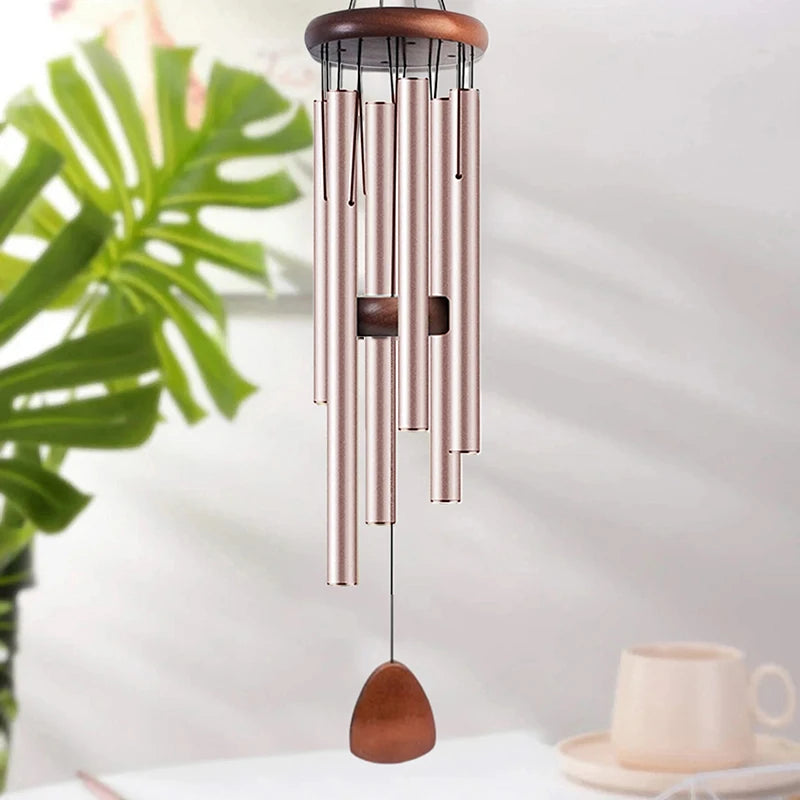 Carillon suspendu en tubes d'aluminium rose gold et en bois, exposé sur un fond lumineux.