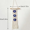 Macrame wall hanging featuring multiple blue evil eye pendants on a cream-colored cord.