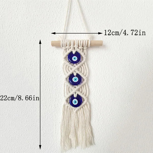Macrame wall hanging featuring multiple blue evil eye pendants on a cream-colored cord.