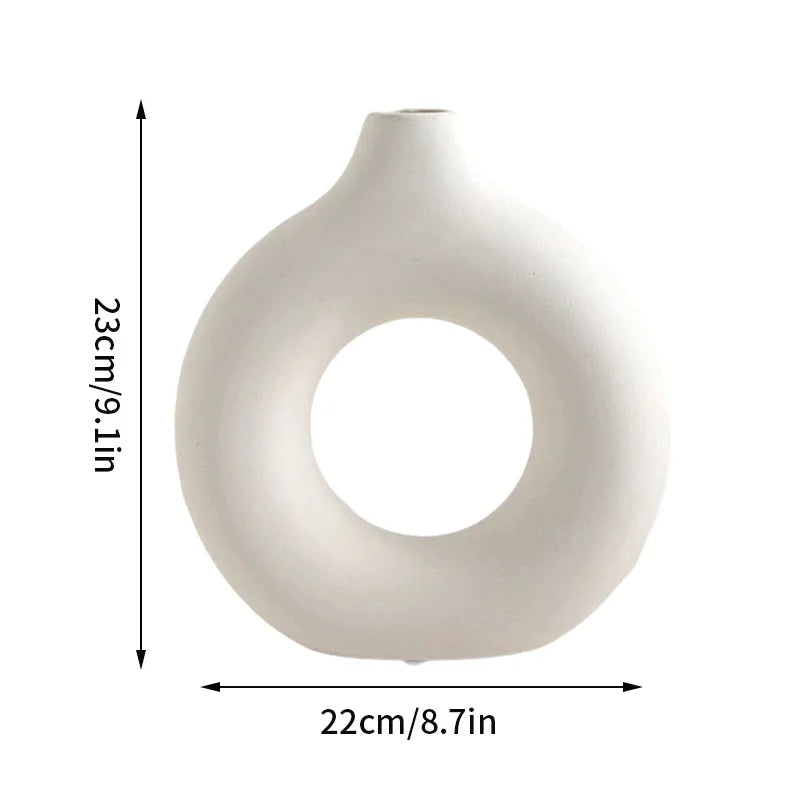 White ceramic vase shaped like a donut with a wide opening.