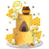 A yellow birthday cake decorated with honeycomb shapes, white and yellow spheres, and a brown honey jar topper.