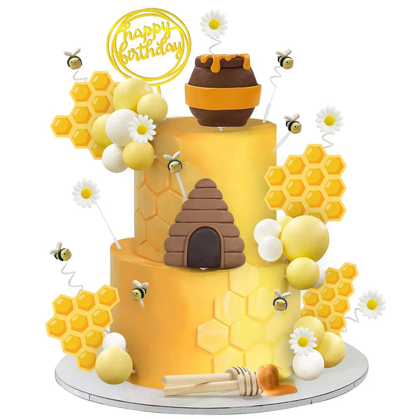 A yellow birthday cake decorated with honeycomb shapes, white and yellow spheres, and a brown honey jar topper.