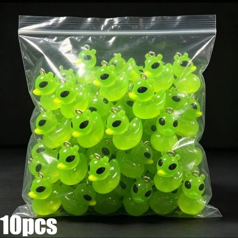 A clear plastic bag filled with 10 pieces of glow-in-the-dark resin alien cat and duck charms.