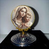 A framed image of the Virgin Mary and the Christ Child in a halo set on a decorative gold stand.