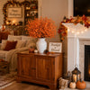 A wooden cabinet displaying artificial orange baby's breath flowers and fall decor on a mantelpiece.