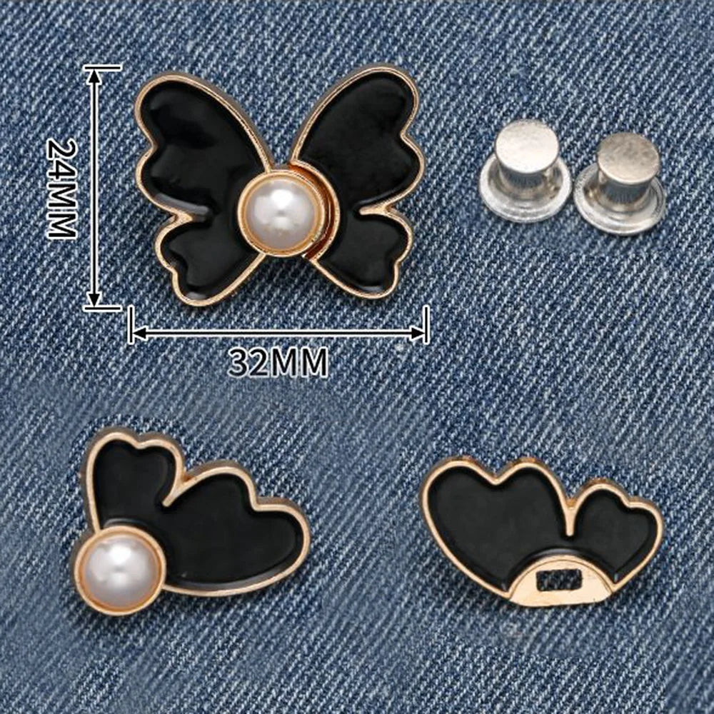 A set of black butterfly waist tightener buttons with pearl accents shown against a denim background.