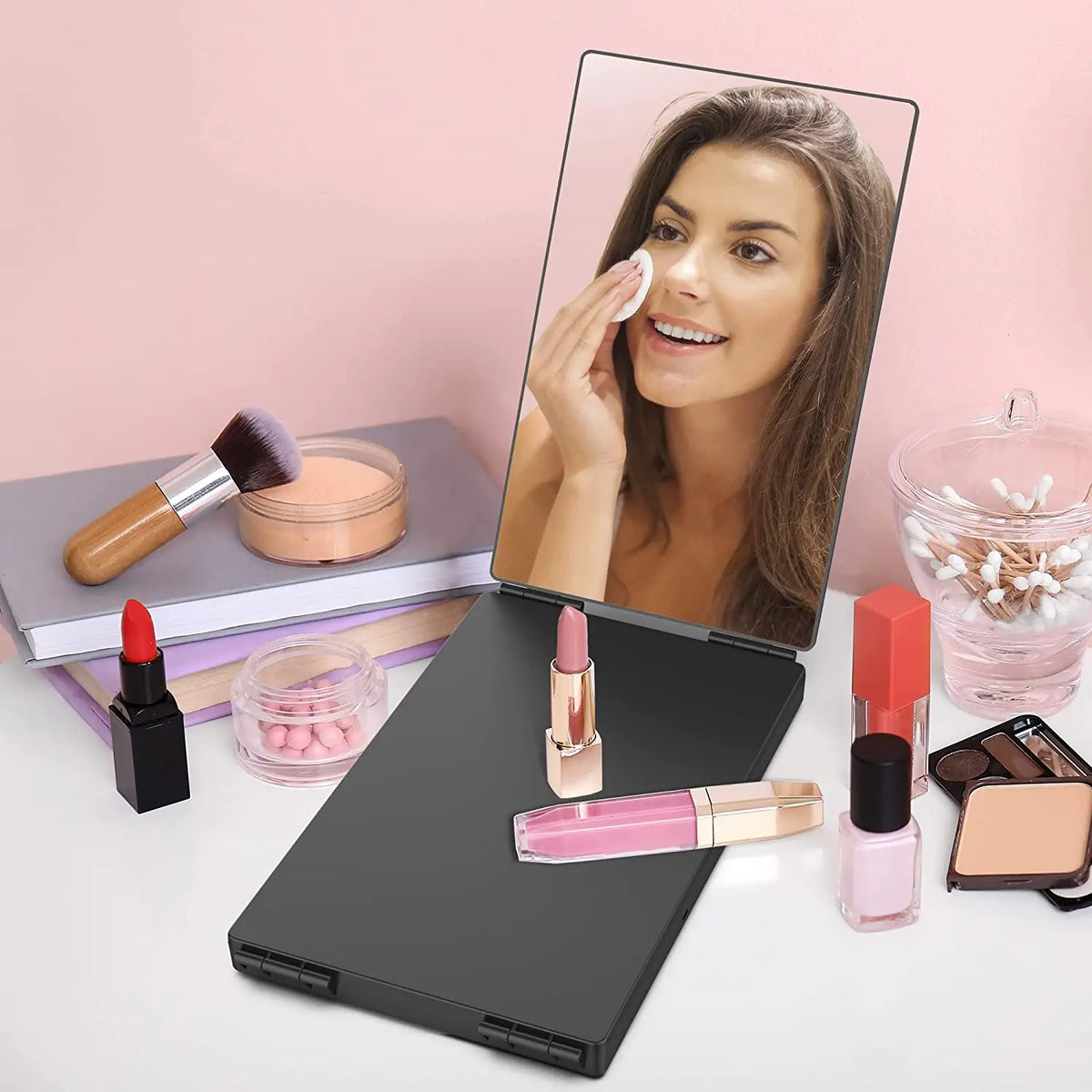 A portable trifold vanity mirror is shown next to makeup products and a woman using the mirror.