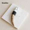 A natural crystal Herkimer scepter wand with a marbled white handle and black cord wrap resting on a white square surface.