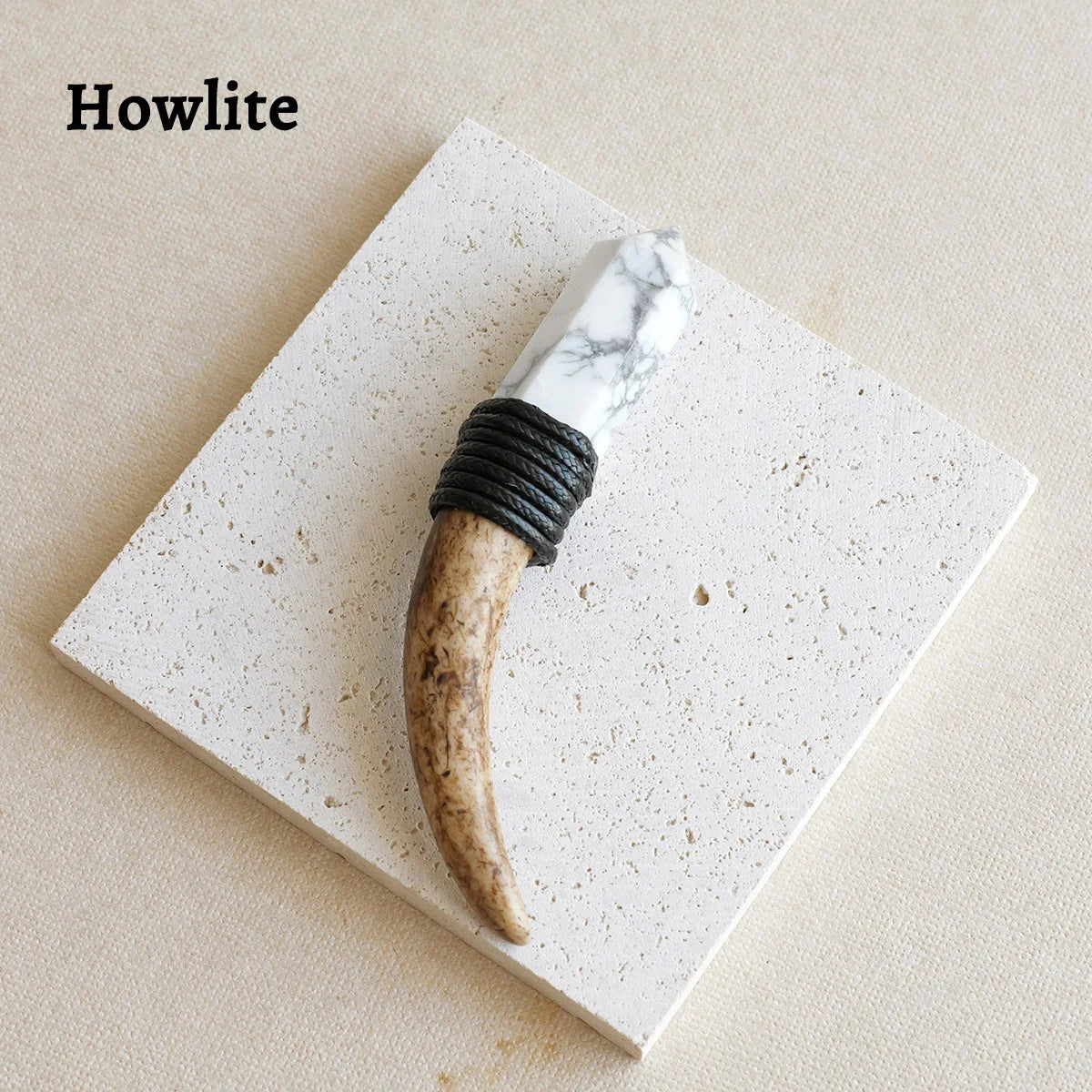 A natural crystal Herkimer scepter wand with a marbled white handle and black cord wrap resting on a white square surface.